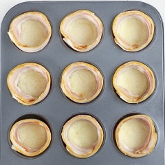 Tiếp đến, cuộn thịt xông khói vào thành khuôn, sau đó cho khoảng 1/2 muỗng canh phô mai cheddar vào khuôn, cho tiếp 1 quả trứng gà rồi rắc thêm muối và tiêu. Cuối cùng, cho khuôn vào nướng 170 độ C trong khoảng 10 - 15 phút là hoàn thành.