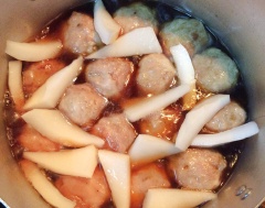 Tiếp đến, cho các viên thịt đã chiên vào nồi cùng với cùi dừa, 1 muỗng canh nước mắm, 1/4 muỗng cà phê tiêu. Đun sôi với lửa to rồi hạ nhỏ lửa, riu đến khi nước keo lại thì nêm 1 muỗng cà phê bột ngọt, trộn đều cho thấm gia vị rồi tắt bếp.