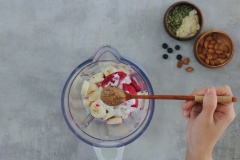 Tiếp đó bạn cho chuối, thanh long đỏ đã cắt lát cùng 100gr sữa chua không đường, 1 muỗng bơ hạnh nhân vào máy xay sinh tố. Xay nhuyễn ở công suất cao đến khi sinh tố nhuyễn mịn.
