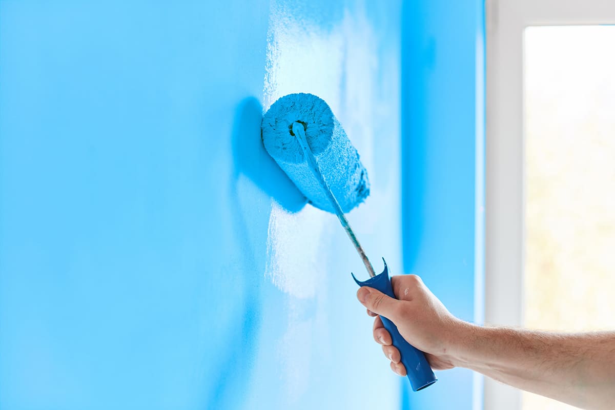 Pintor profesional aplicando pintura azul con rodillo en vivienda de Tenerife