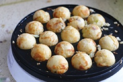 Đặt khuôn chuyên dụng để chiên bánh tokoyaki lên bếp ở lửa nhỏ, phết đều dầu ăn lên từng khuôn. Tiếp theo, đổ hỗn hợp bột vào ngập nửa khuôn bánh. Cho bạch tuộc cùng hành tây và bắp cải đều lên trên mặt bột. Tiếp tục đổ bột vào đến khi tràn đầy khuôn. Sau đó, đợi bột chín trong vòng 2-3 phút rồi dùng xiên que lật một góc 45 độ để định hình cho bánh tròn. Lặp lại động tác xoay bánh bằng que tăm vài lần đến khi bánh vàng giòn.