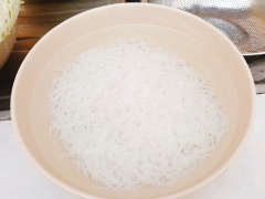 Thịt bò thái lát mỏng. Tỏi bóc vỏ rồi băm nhuyễn. Ướp thịt với 2 muỗng canh nước tương, 1 muỗng cà phê hạt nêm, 1/3 tỏi băm. Trộn đều cho thịt thấm gia vị. Bún gạo ngâm với nước lạnh từ 10 - 15 phút. Sau đó đun sôi một nồi nước, cho bún gạo vào nấu khoảng 5 - 7 phút, bún gạo mềm thì vớt ra tô nước lạnh cho sợi bún được tơi. Vớt ra rổ để ráo.