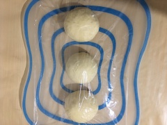 Nhồi sơ bột bánh mì rồi chia là 3 khối đều nhau, vê hơi tròn, bọc màng thực phẩm ủ bột bánh mì khoảng 15 phút.