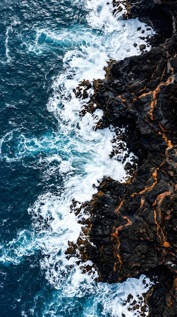 Vertical Aerial View of Black Volcanic Rock Meeting Deep Blue Ocean - Free mobile Wallpaper