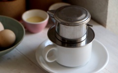 Cho vào phin 2 muỗng cà phê, dùng gạt ép cà phê vừa phải, không quá chặt cũng không quá lỏng. Đầu tiên bạn rót vào 20ml nước sôi, để khoảng 15 giây cho cà phê ngấm rồi tiếp tục cho 60ml nước sôi còn lại. Đậy nắp phin và chờ cà phê rơi xuống đến khi hết nước.