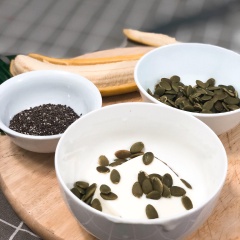 Cho sữa chua vào tô, rắc hạt bí và hạt chia vào. Cuối cùng xếp chuối đã cắt lát lên xung quanh chén.