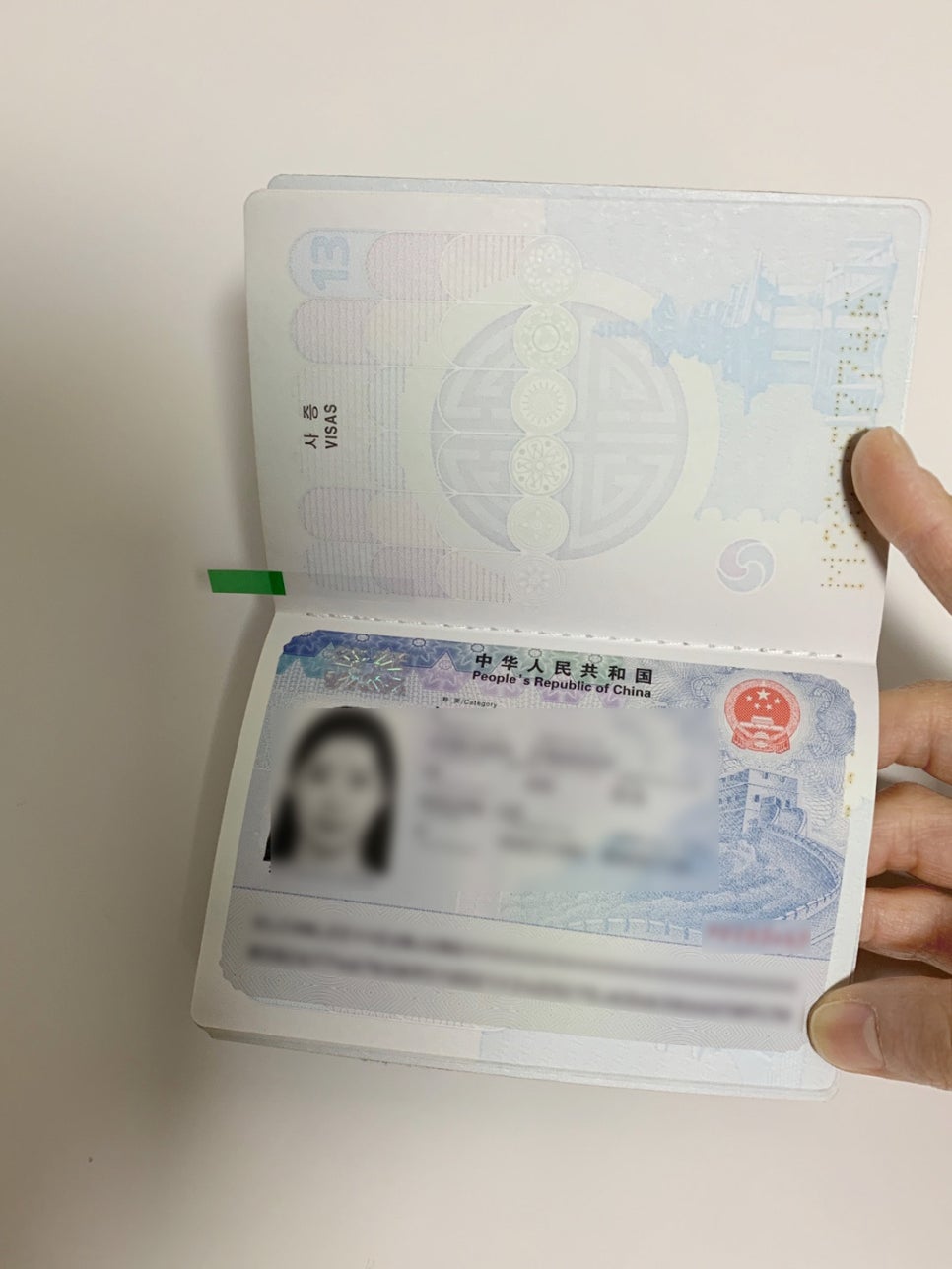 여권 사증란에 부착된 중국 비자 면을 펼쳐 발급 내용을 확인하는 모습