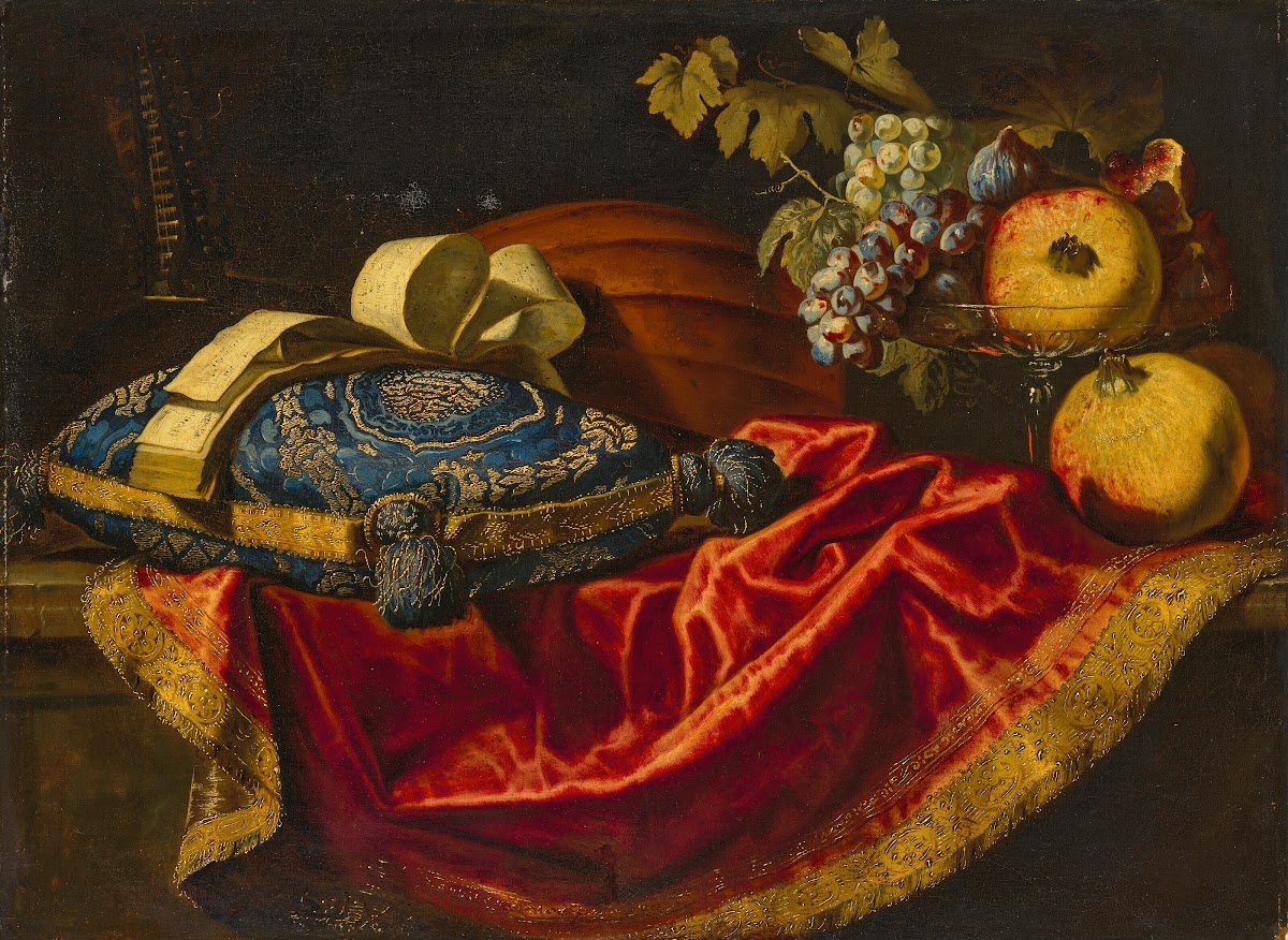 A mandolin with a book of music on a blue and gold cushion with fruit on a parti