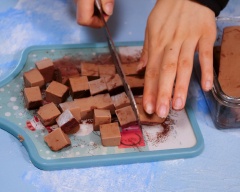 Bạn rắc phần bột cacao còn lại lên thớt, lấy phần nama trong tủ lạnh ra đổ lên thớt và cắt thành từng miếng vuông vừa ăn. Áo các viên nama một lớp cacao sao cho chúng bám đều hết vào nama là được nha. Vậy là chúng ta có thể thưởng thức rồi đó.