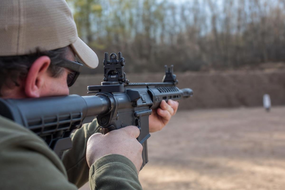 AR-15 backup sights mounted on a flat-top upper receiver at an outdoor range