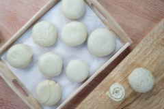 Đặt viên nhân bánh pía vào giữa miếng bột vỏ, cho trứng muối vào rồi gói lại cho kín nhân, dùng tay nắn nhẹ để được khối cầu đều. Bạn cần gói cho lớp vỏ bánh pía Sóc Trăng bám sát viên nhân bánh, dính mép bột chặt tay để nhân không bị hở ra ngoài khi nướng. Phần bột thừa ra bạn dùng tay túm chặt lại giống như túi gói quà. Quay phần túm bột xuống dưới làm đế bánh pía Sóc Trăng. Đặt bánh đã nặn xong lên khay nướng có lót giấy nến chống dính. Dùng tay đè cho bánh pía Sóc Trăng hơi dẹt xuống, bề mặt bánh bằng phẳng.