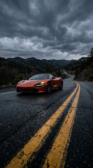 Orange High-Performance Sports Car on Dark Asphalt Road Under Stormy Clouds - Free mobile Wallpaper