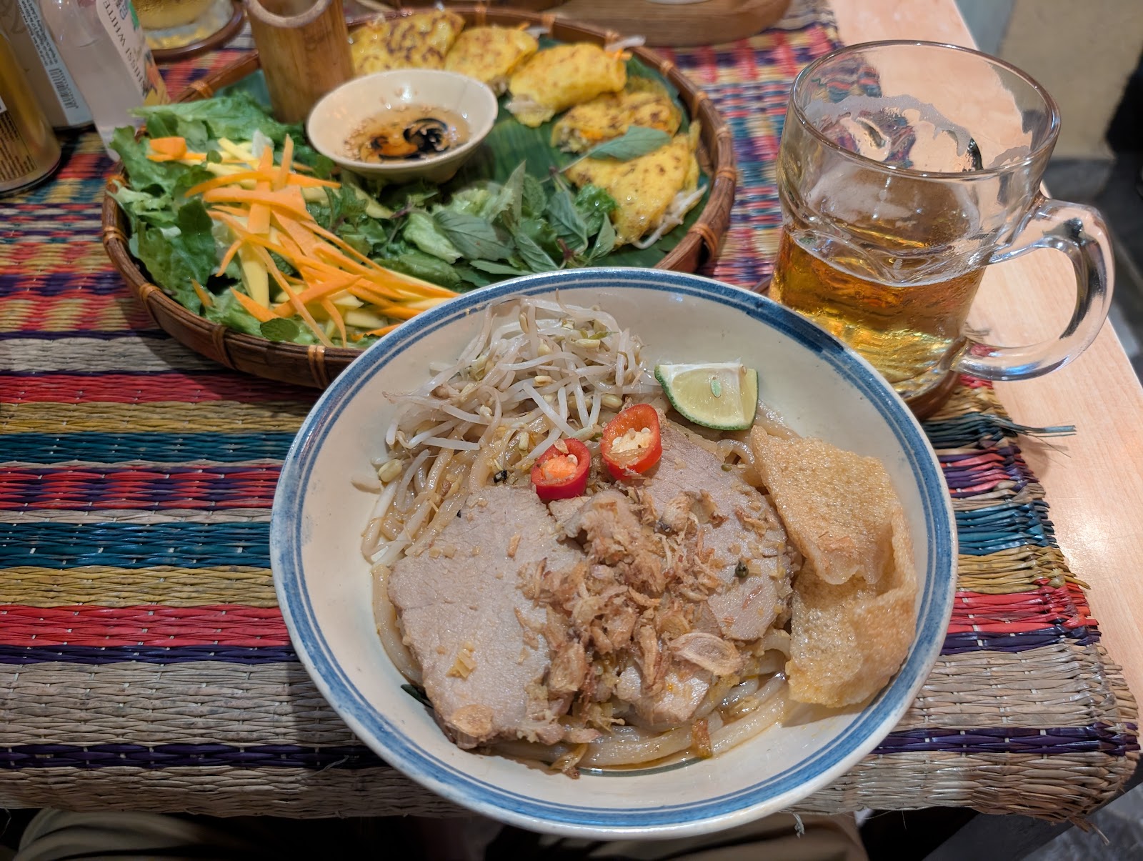 Photo of a bowl of thick noodles with thick slices of pork on top.
