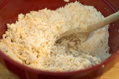 Bật lò ở 180 độ C. Cho bột mì, phô mai cheddar cùng với đường vào tô, trộn đều với nhau.