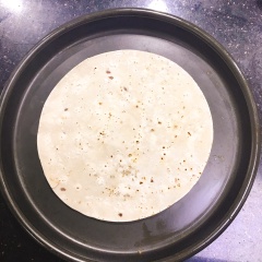 Trải bánh tortilla trải lên mâm nướng, tiếp theo cho bắp cải và trải đều mặt (nhớ là không nên cho ra ngoài bìa bánh). Thêm mozzarella vào giữa bánh + xúc xích cắt sợi + trứng gà đánh tan và cuối cùng là xịt sốt teriyaki lên trên bề mặt để bánh được thấm và ngon hơn.