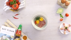 Đập 2 quả trứng gà vào tô trộn, thêm thịt xông khói, ngò tây băm nhuyễn và ớt băm. Nêm gia vị với 1 muỗng canh xốt nêm Knorr thịt gà cho hương vị thêm đậm đà, trộn đều cho hỗn hợp hoà quyện.