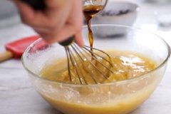 Làm nóng lò nướng ở nhiệt độ 180 độ C. Rắc một chút bột làm bánh vào khuôn bánh. Chuối bóc vỏ, nghiền nhuyễn. Thêm bơ, đường, trứng, tinh dầu vani vào trộn đều tạo thành hỗn hợp đồng nhất.