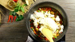 Khi sốt cà ri sôi cho vào chảo phần thịt gà đã ướp cùng 50gr cà rốt, 50 gr đậu côve và 50gr ớt chuông cắt hạt lựu. Đảo đều đến khi gà gần chín thì cho 200gr cơm vào trộn đều với nhau. Phần cơm để chiên nên nấu hơi khô một chút để khi đảo cơm sẽ không bị quá dính, gây ngán khi ăn. Cuối cùng rắc lá chanh và lá húng quế vào phần cơm đã trộn cho thơm. Vậy là món cơm chiên cà ri xanh đã hoàn thành.