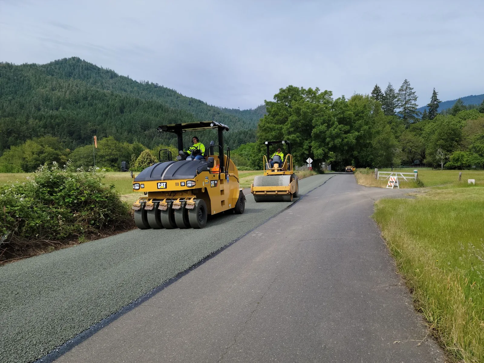 Road rollers work on asphalt paving in the scenic countryside near Agness, Oregon.