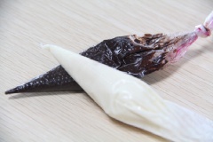 Đun chảy riêng biệt chocolate trắng và đen rồi cho riêng vào 2 túi bóp kem. Tranh thủ lúc chocolate còn lỏng tiến hành trang trí những chiếc bánh quy thành hình những con nhện dễ thương nhé!