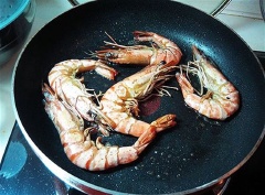 Cho 2 muỗng canh dầu ăn vào chảo, đun nóng rồi cho tôm vào chiên. Chiên đều hai mặt chín đỏ hồng rồi gắp ra đĩa.