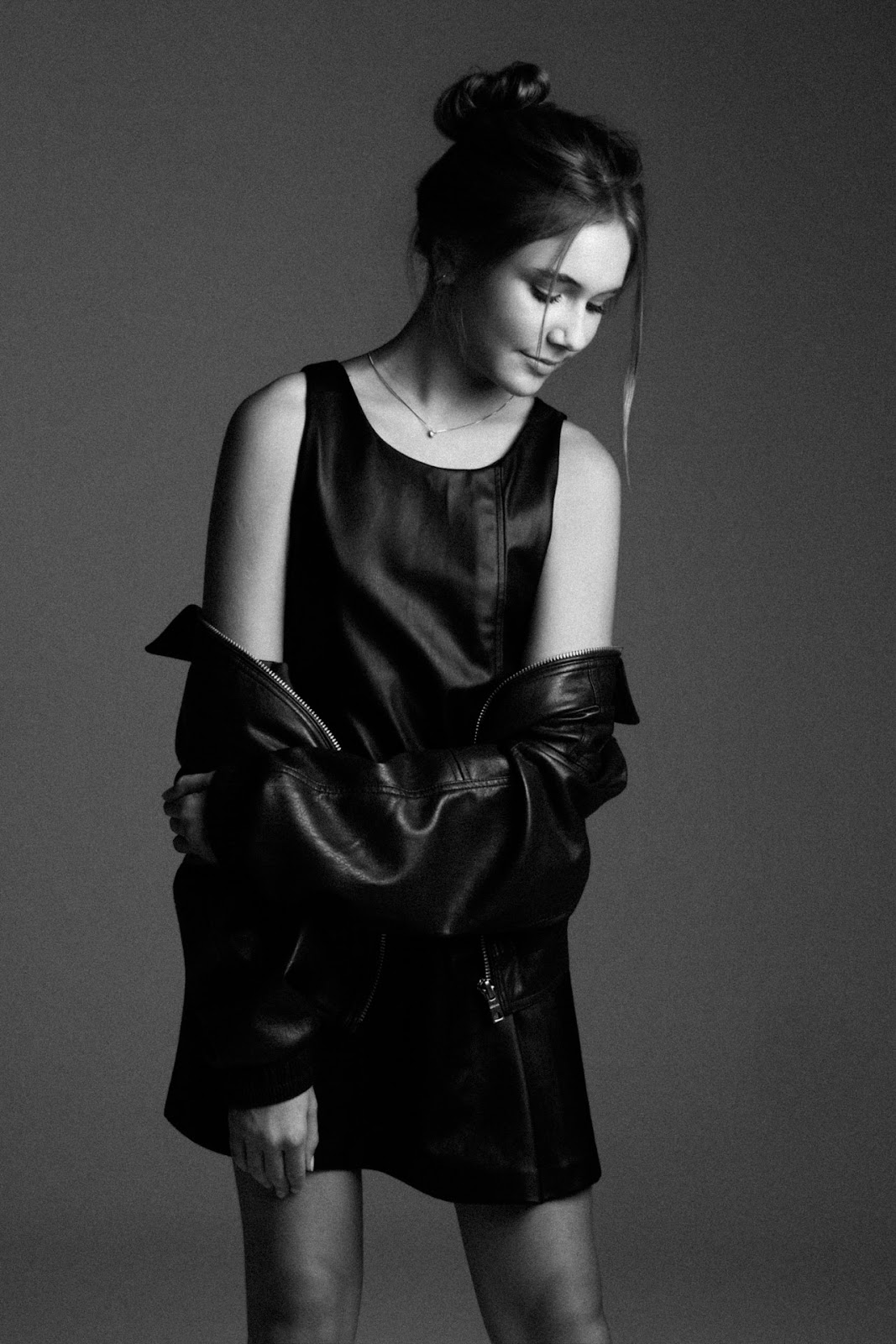 Retrato em preto e branco de Maria Luiza com coque, vestido escuro e jaqueta de couro ca�da nos bra�os.