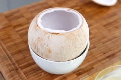 Dùng dao chặt phần đầu trên cùi dừa. Đổ nước dừa ra cốc và đặt vỏ trái dừa lên 1 cái chén.