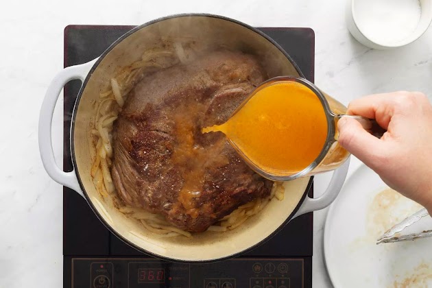 Caldo vertido sobre el asado y las cebollas selladas en el horno holandés.