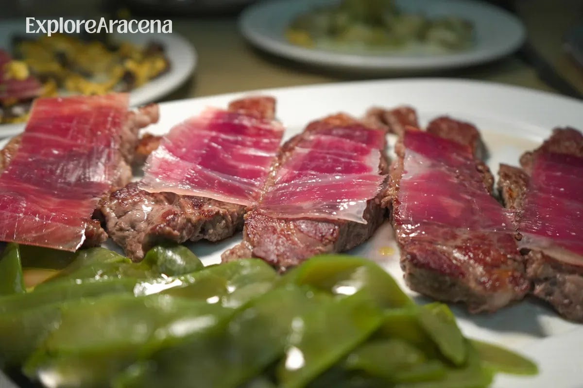 Sliced presa ibérica topped with fine pieces of jamón and served alongside grilled green peppers at Brioso Restaurante.