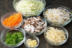 Chuẩn bị tất cả nguyên liệu. Rửa sạch rau củ, cắt nhỏ hành lá, băm nhỏ gừng tỏi, cắt lát nấm và cắt sợi bắp cải, cà rốt và măng tươi.