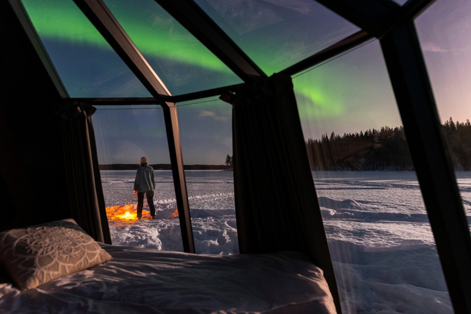 Glass-roofed igloo in Finnish Lapland beneath a dark Arctic sky, designed for Northern Lights viewing.