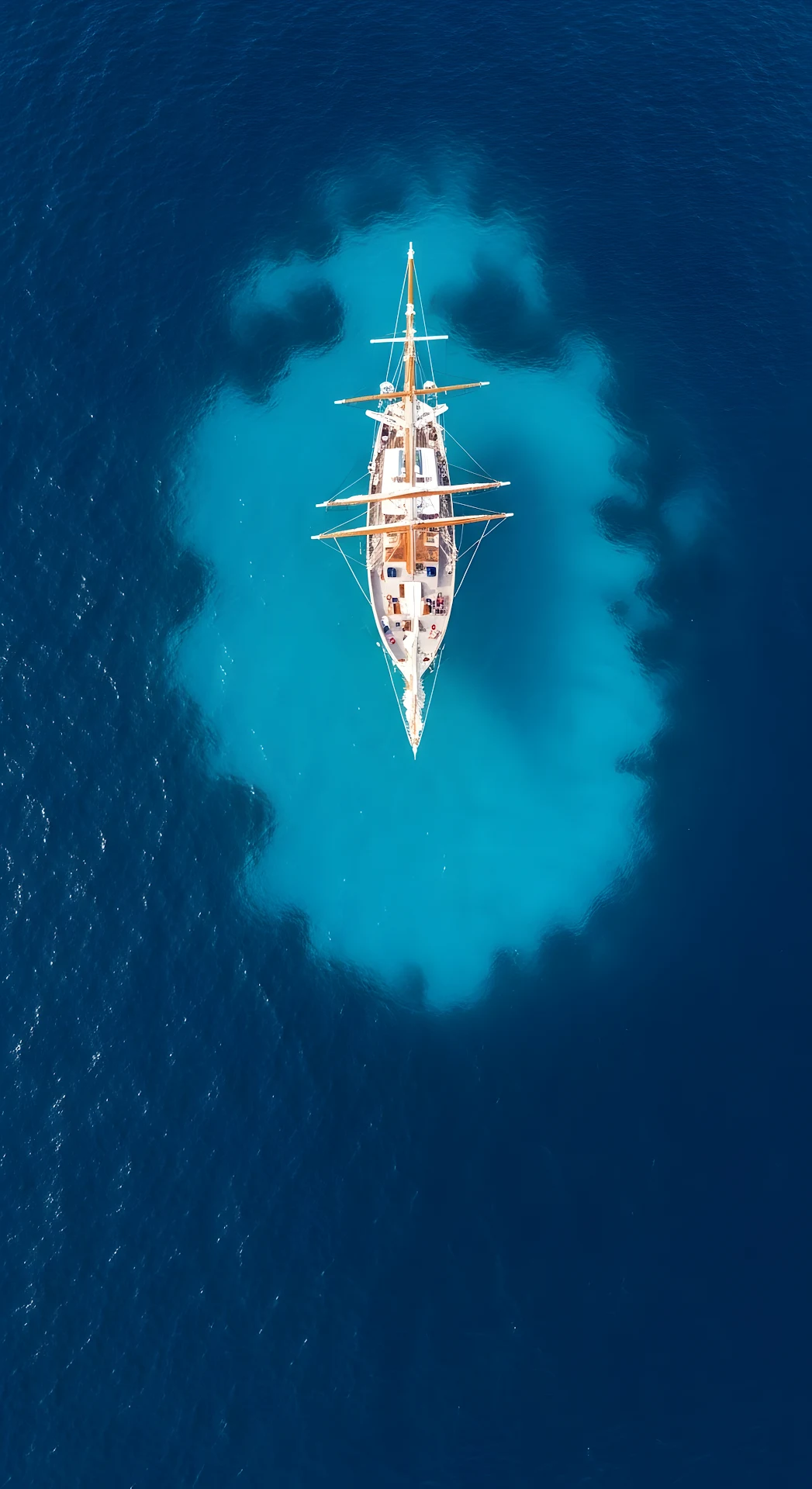Overhead Aerial of a Classic Schooner Sailboat in Deep Blue Turquoise Ocean Water - Free 4K mobile Wallpaper