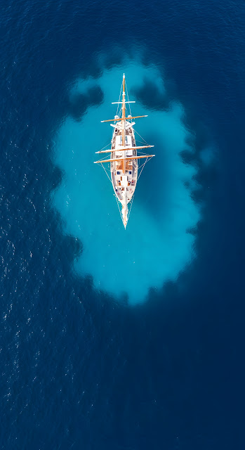 Overhead Aerial of a Classic Schooner Sailboat in Deep Blue Turquoise Ocean Water - Free mobile Wallpaper
