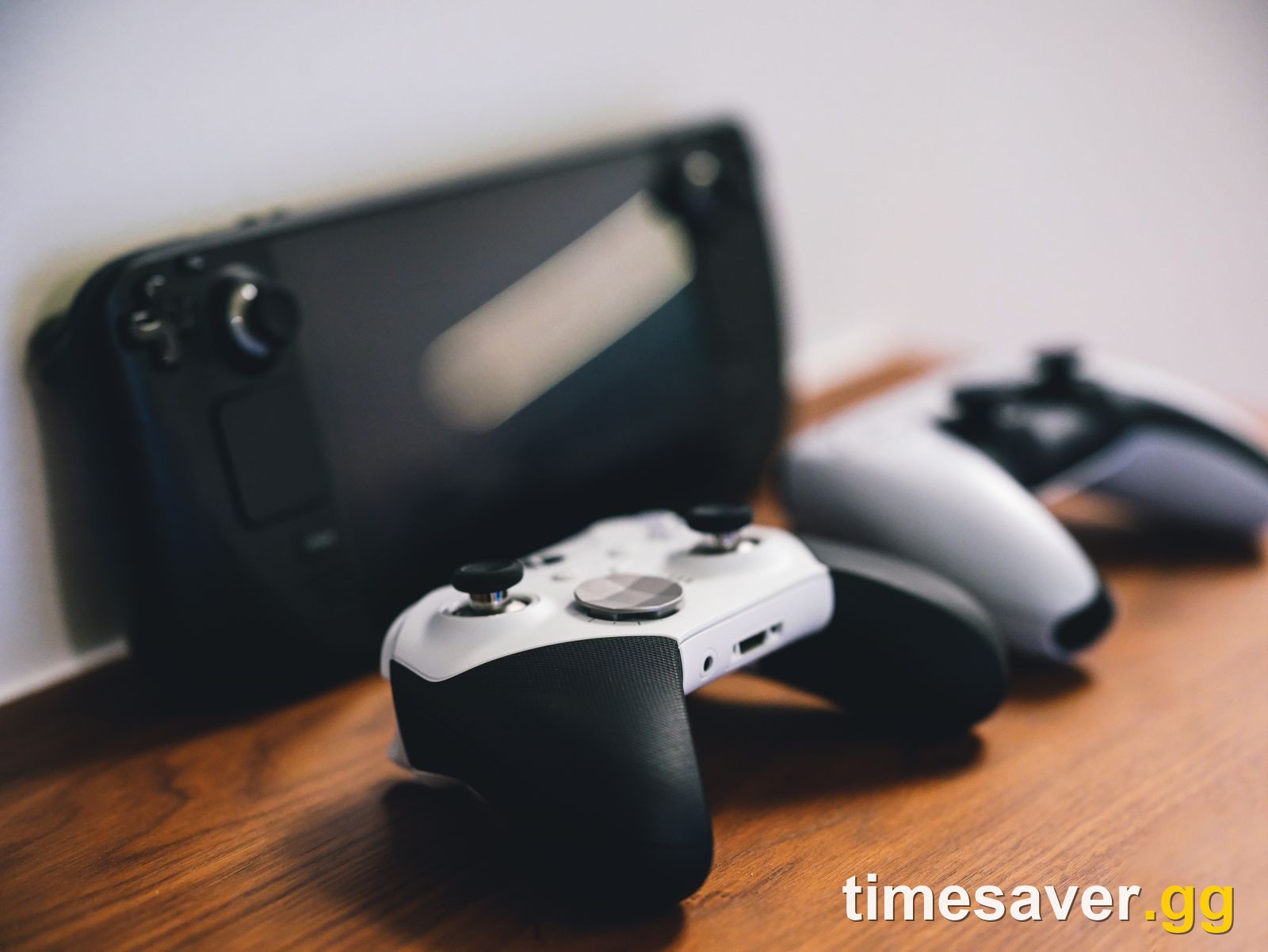 Game controllers and a handheld console on a desk, representing FC 27 trading across platforms