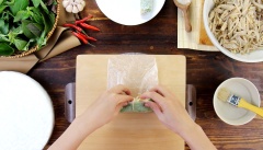 Trải bánh tráng ra mặt phẳng, phết nước để làm mềm mặt bánh, thêm vào rau tùy thích, da và thịt heo đã trộn thính rồi cuộn lại thành cuốn to. Làm tương tự cho đế hết nguyên liệu.