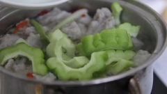 Đợi nước sôi, chả cắt vo thành viên vừa ăn rồi thả vào vào nồi nước, sau khi chả cá nổi lên trên mặt nước thì cho khổ qua vào nấu cho nước trong nồi sôi lại khoảng 3 phút thì tắt bếp. (Nếu bào mỏng thì chỉ cần nước sôi lại là có thể tắt bếp rồi)