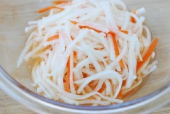 Sau khi ngâm muối, sợi cà rốt và củ cải đã mềm hơn, dùng tay vắt sạch nước còn lại trong củ cải và cà rốt cho vào tô để riêng. Trong 1 tô lớn, hòa tan đường với 1/4 muỗng cà phê muối, giấm và ớt bột. Sau đó cho vào tô cà rốt và củ cải, trộn đều lên.