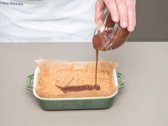 Bắc 1 nồi nước nhỏ lên bếp và đun sôi. Cho phần chocolate đen vào tô có đáy lớn hơn nồi nước. Đặt tô chocolate lên nồi nước sôi rồi khuấy chocolate tan chảy. Rót phần chocolate đó lên phần bánh đã đông. Làm lạnh cho tới khi bánh đông thì cắt bánh thành thanh dài.