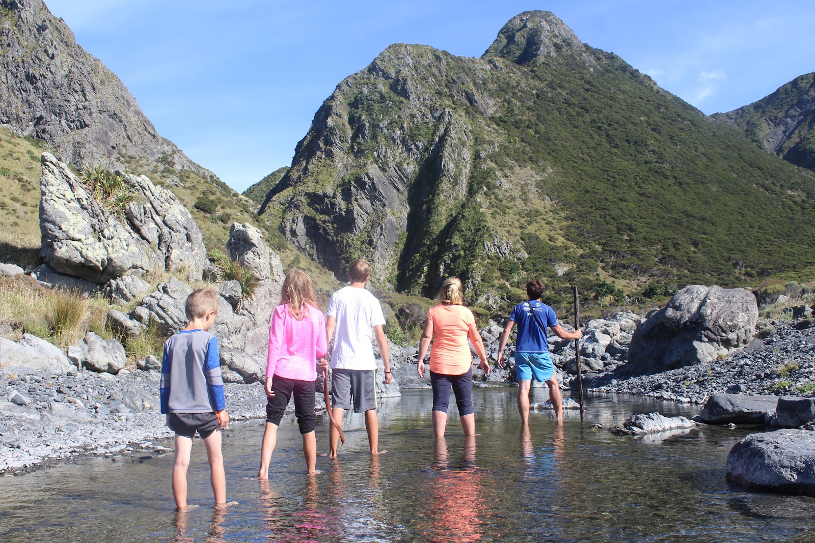 A family wading up a mountain stream in New Zealand