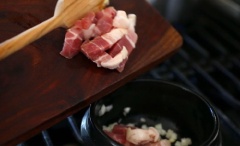 Làm nóng một nồi đất (kiểu Hàn), trên bếp với lửa lớn khoảng 3-4 phút. Thêm dầu ăn, hành tây, tỏi vào. Đảo đều trong 1 phút. Cho thịt heo vào, đảo trong 3 phút cho đến khi thịt không còn màu hồng.