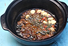 Đặt thố đất lên bếp, cho 2 muỗng canh dầu ăn vào, đợi dầu nóng cho 1 muỗng canh đường vào thắng caramel rồi cho hết tép tỏi, tiêu giã dập và ớt xắt nhuyễn vào, phi cho thơm. Cho thêm 2 muỗng đường còn lại, 1/2 chén nước mắm vào thố, khuấy đều, nấu sôi, tắt bếp. Lúc này ta sẽ có được hỗn hợp ướp cá rất ngon và màu đẹp.
