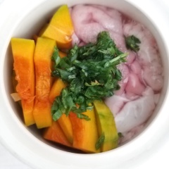 Cho bí đỏ đã cắt vào 1 góc chum óc heo. Hành lá + ngò rí cắt nhuyễn cho lên mặt óc. (nếu người lớn ăn thì cho thêm ít tiêu xay và hành tím cắt lát thì óc sẽ thơm hơn). Đậy nắp chum lại.