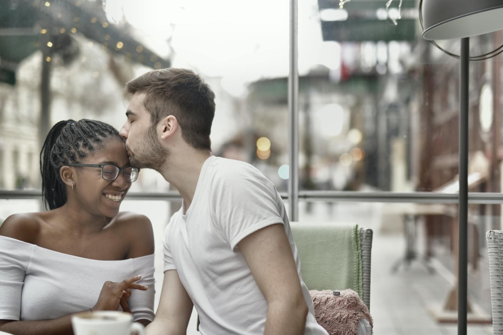 A happy diverse couple connecting in a coffee shop, emphasizing the goal of finding genuine love with AI dating apps.