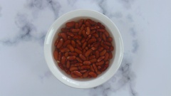 Rửa sạch 200gr đậu đỏ Tây, ngâm qua đêm cho đậu nở lớn rồi cho vào nồi nấu chín cùng khoảng 2 lít nước. Nấu lửa vừa khoảng 45 phút đến 1 tiếng đến khi đậu mềm, hạt vỡ ra được thì tắt bếp.