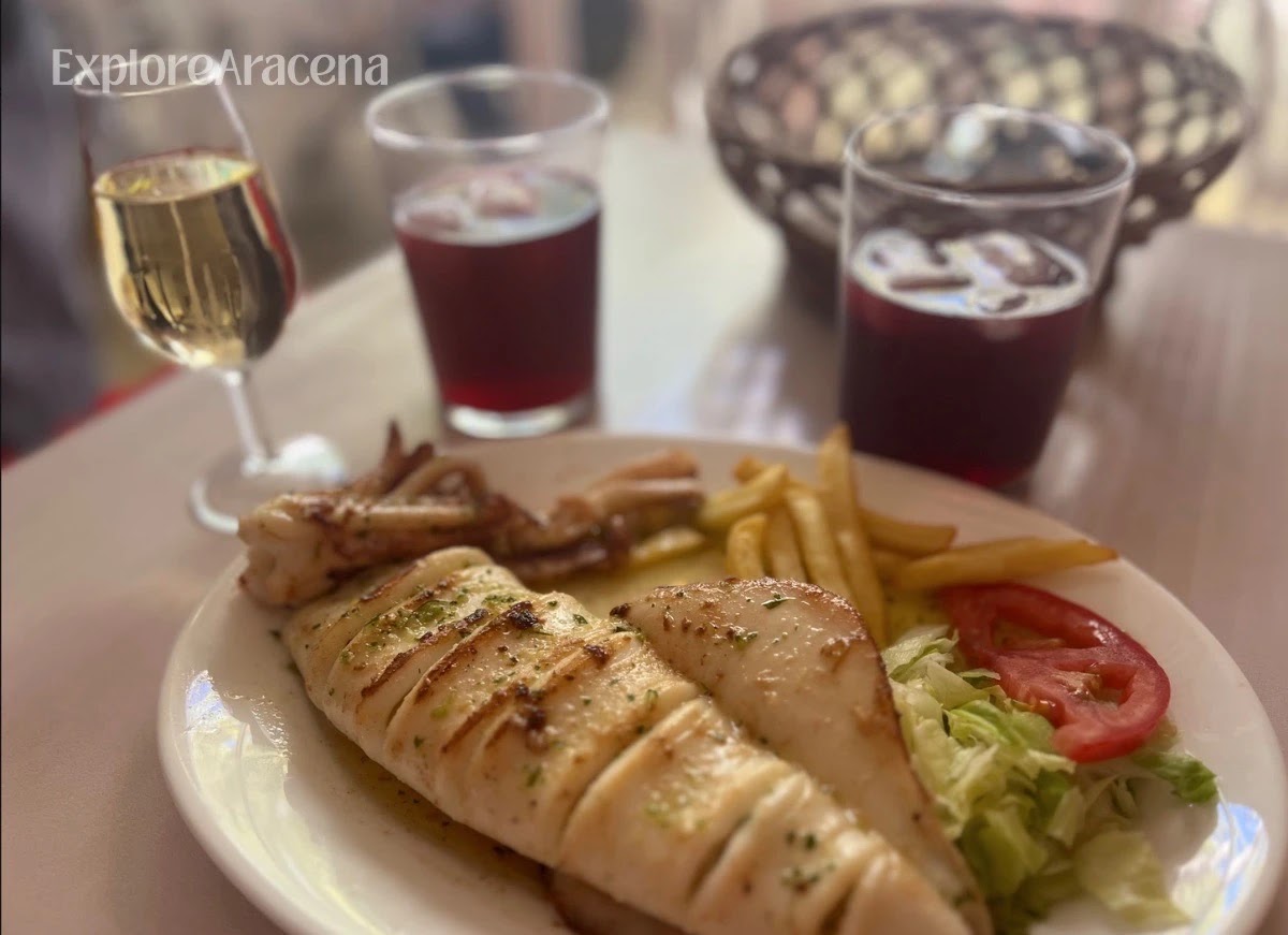 Feria table with wine, tinto de verano and a plate of food during lunch inside a caseta.