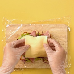Lấy 1 lát bánh mì sandwich, dùng muỗng phết 1 lớp sốt ca ngừ, sau đó đặt lát bánh lên trên thớt có trải lớp màng bọc thực phẩm, đặt 2 lá xà lách, 2 lát cà chua, 1 lớp bắp cải tím thái nhỏ, 1 lớp thịt nguội, 1 lớp dưa leo thái lát, 1 quả trứng luộc lòng đào, 1 miếng phô mai, 1 lớp cà rốt, 1 lớp bơ.