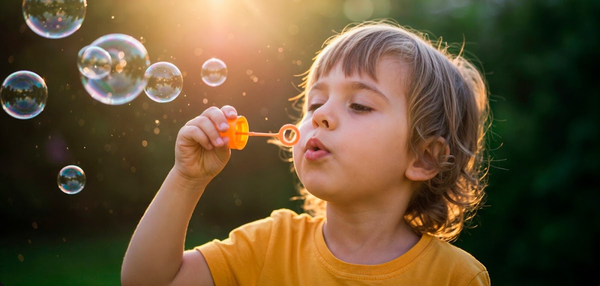 Child blowing soap bubbles outdoors
