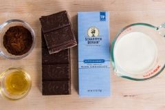 Cắt nhỏ chocolate đen và cho vào tô (bạn nên dùng dao thật bén để cắt chocolate nha). Lót giấy nến vào khuôn hình vuông bằng thủy tinh. Chế 200ml heavy cream vào nồi, đặt lên bếp nấu sôi trên lửa vừa. Khuấy đều heavy cream bằng phới lồng, khi thấy có bọt bong bóng nhỏ nổi lên thì bạn tắt bếp. Nhấc nồi heavy cream ra ngoài.