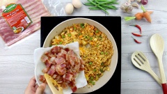 Thêm cơm trắng vào chảo, chiên cho cơm và các loại rau củ sao cho trộn đều vào nhau, cơm áo màu vàng đẹp từ kim chi. Nêm nếm với 1 muỗng canh nước tương, 1 muỗng canh dầu mè là vừa ăn. Thêm thịt xông khói, hành lá cắt nhỏ vào, đảo đều rồi nhắc xuống.