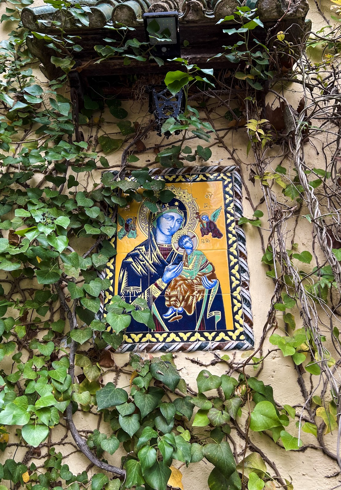 Religious devotional tile on ivy-covered wall